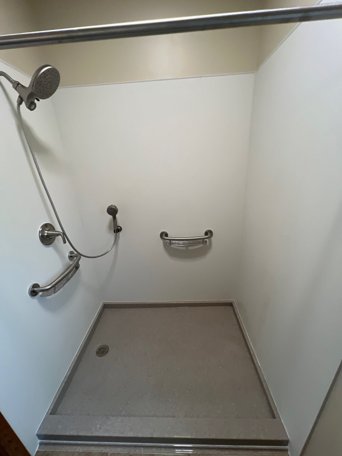 ADA walk-in shower with grab bars and handheld shower head