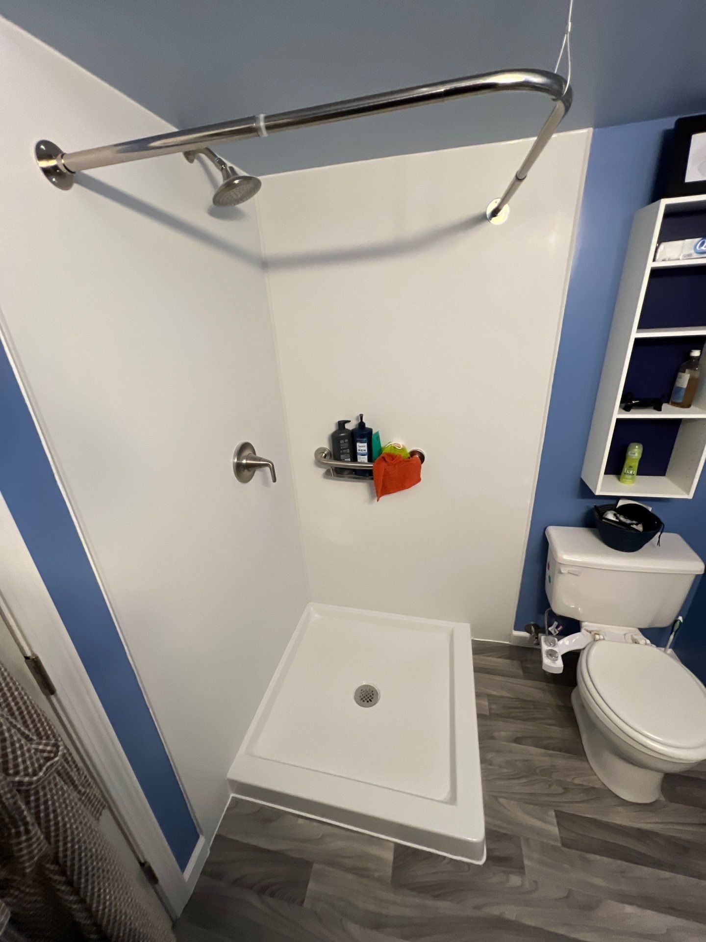 Walk-in shower with grab bars against navy accent wall