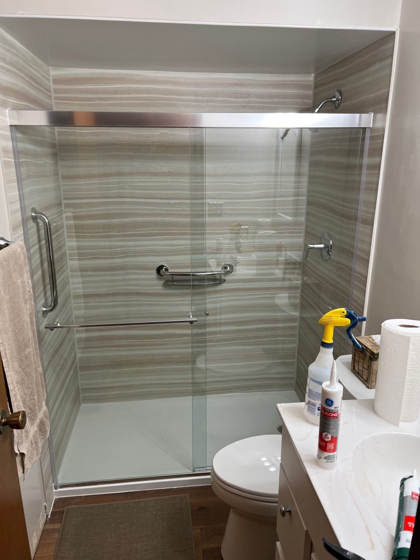 Sliding glass shower door with wood-look tile and grab bars