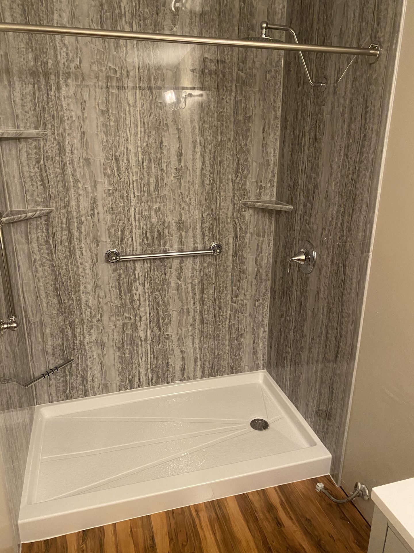Gray wood-look marble shower with grab bar and glass door