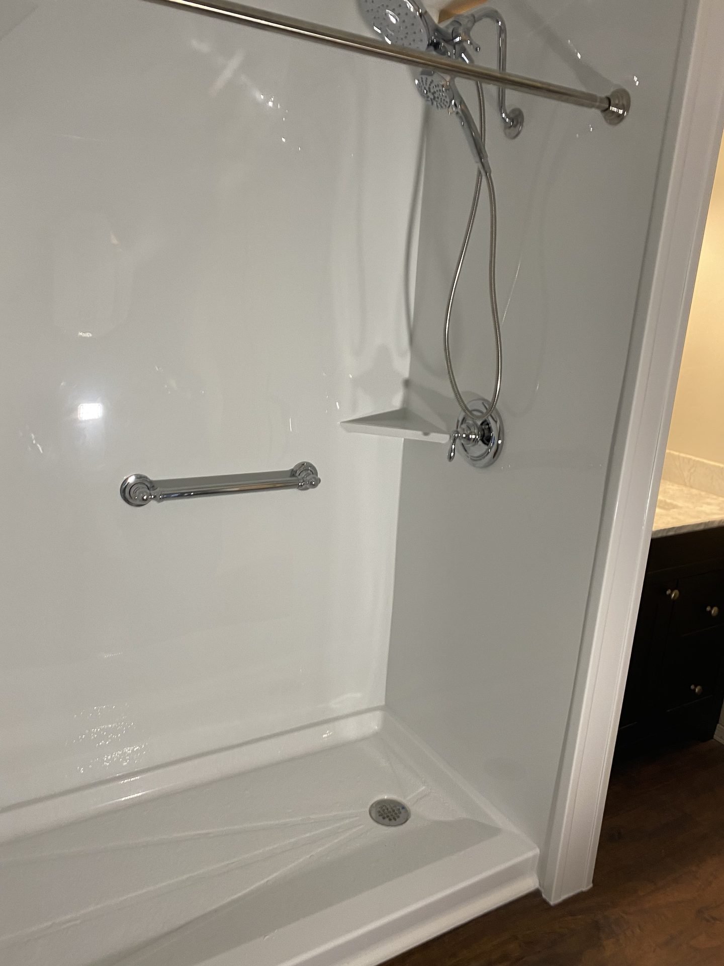 White walk-in shower with corner shelf and grab bar
