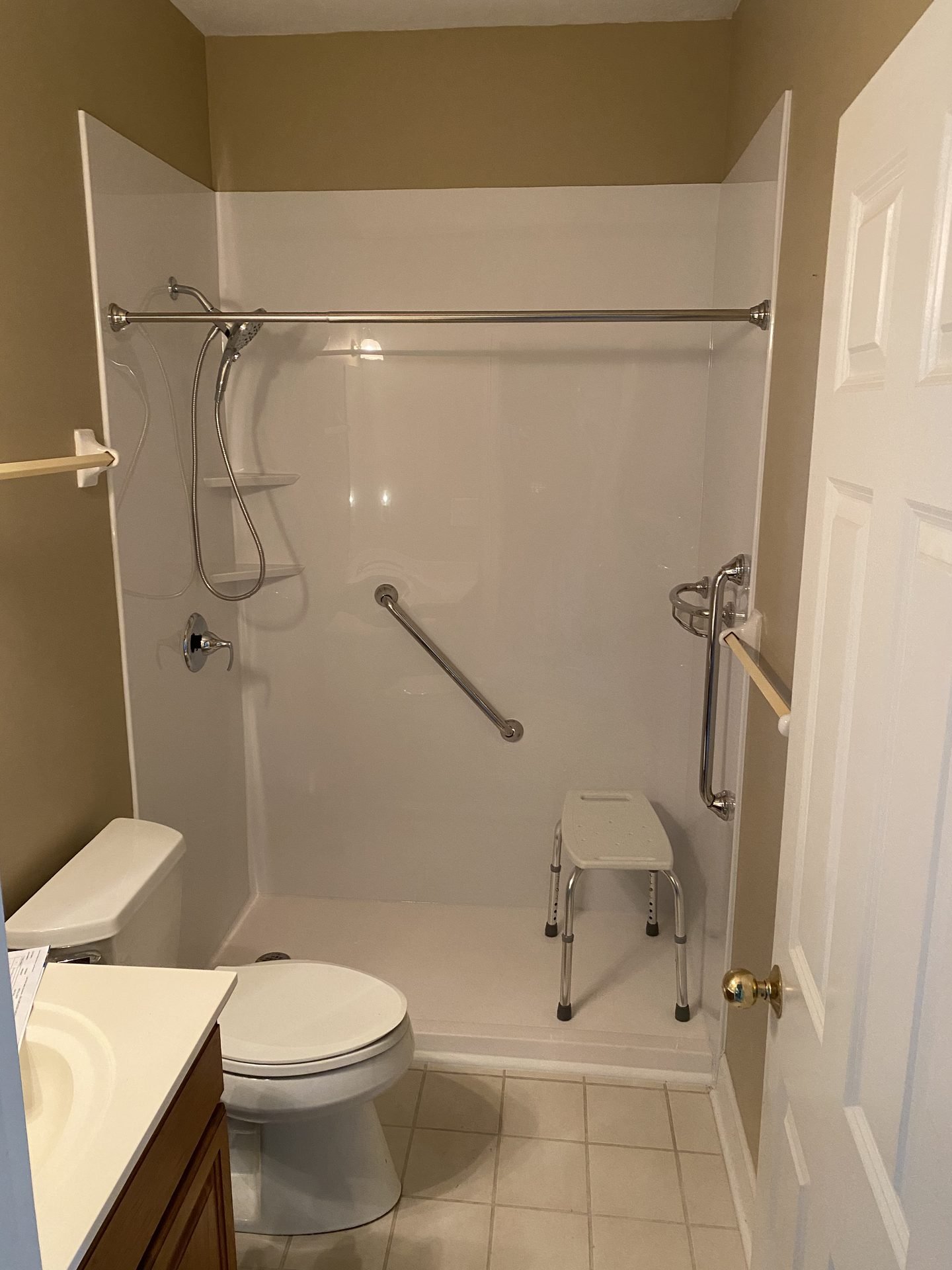 Glass shower stall with marble walls and dark fixtures
