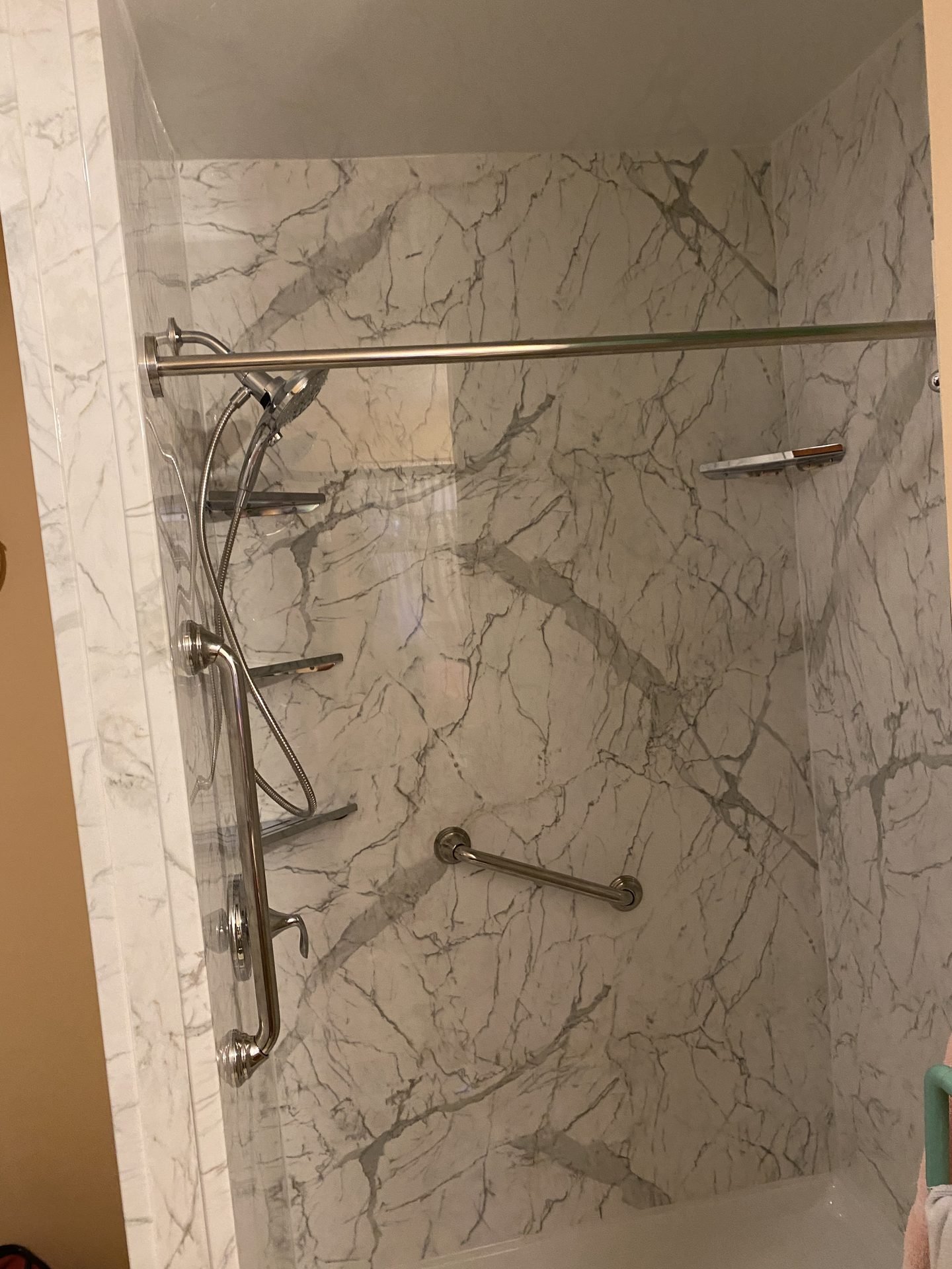 Marble-look shower with corner shelves and grab bar