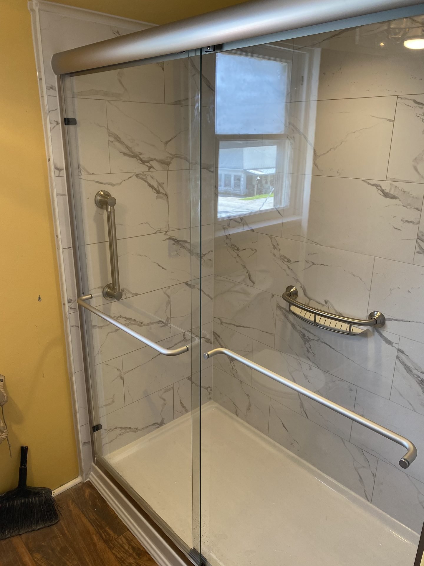 Marble tile shower with sliding glass door and window