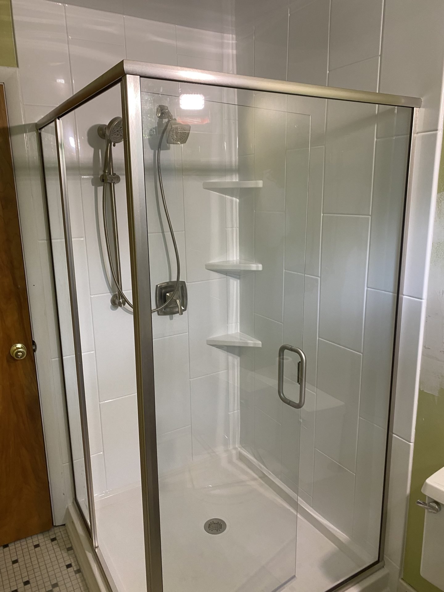 Corner glass shower enclosure with chrome fixtures