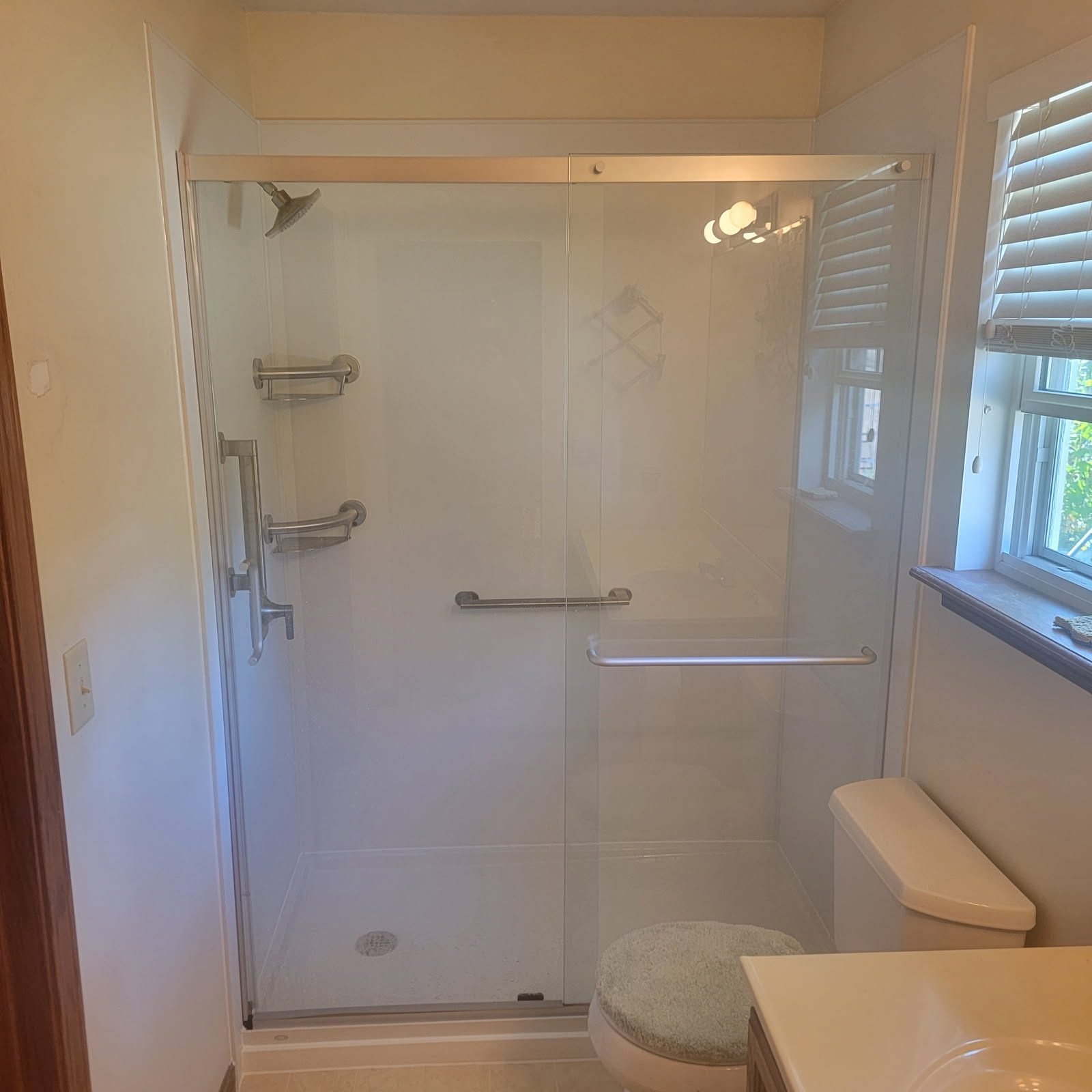 Bright glass shower with window and grab bars